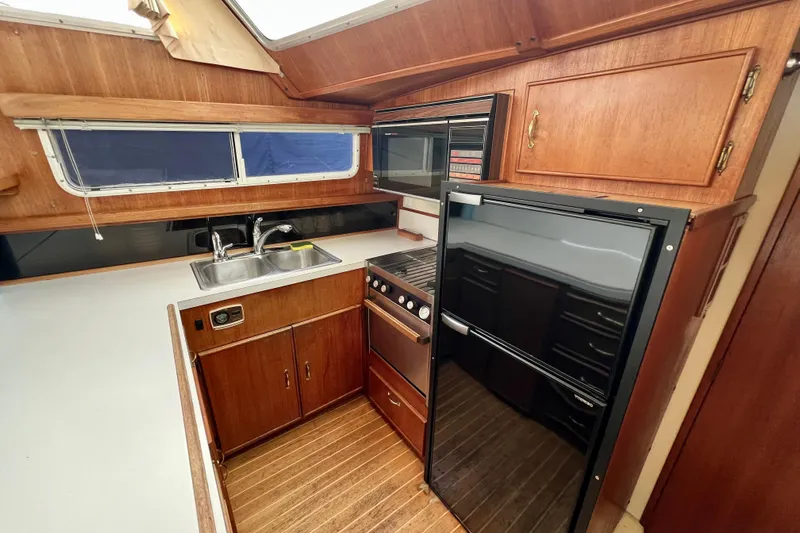 Adios Yacht Photos Pics 1985 Tollycraft 48 Cockpit Motor Yacht kitchen with wood cabinetry and modern appliances.