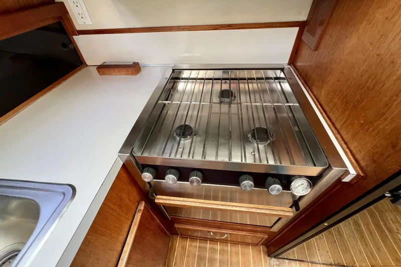 Adios Yacht Photos Pics 1985 Tollycraft 48 Cockpit Motor Yacht kitchen with stainless steel stove and wooden cabinetry.