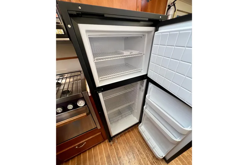 Adios Yacht Photos Pics Open refrigerator in 1985 Tollycraft 48 Cockpit Motor Yacht kitchen, showing shelves and storage.