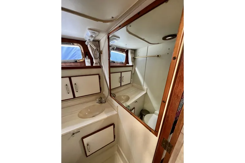 Adios Yacht Photos Pics 1985 Tollycraft 48 Cockpit Motor Yacht bathroom with sink, mirror, and storage cabinets.