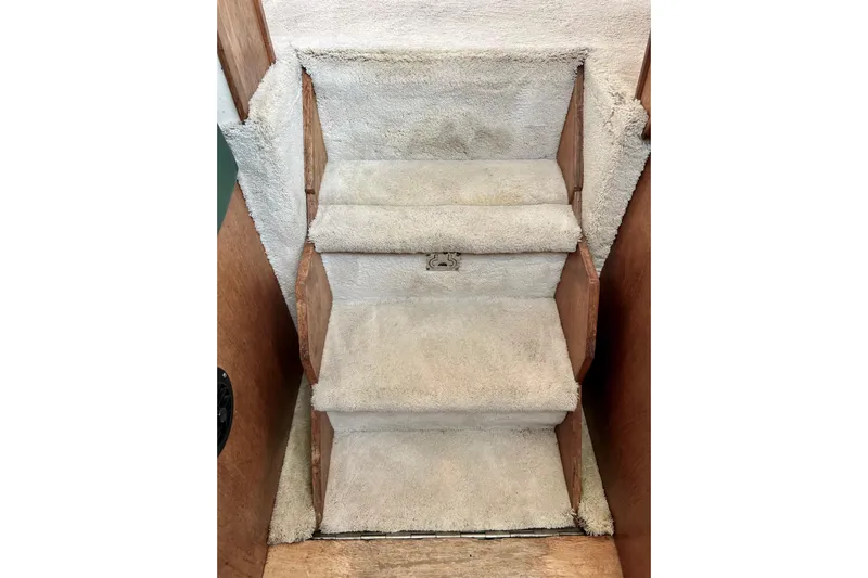 Adios Yacht Photos Pics Carpeted stairs inside 1985 Tollycraft 48 Cockpit Motor Yacht, featuring wooden side panels.