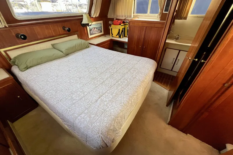 Adios Yacht Photos Pics 1985 Tollycraft 48 Cockpit Motor Yacht bedroom with bed, wood paneling, and small sink area.