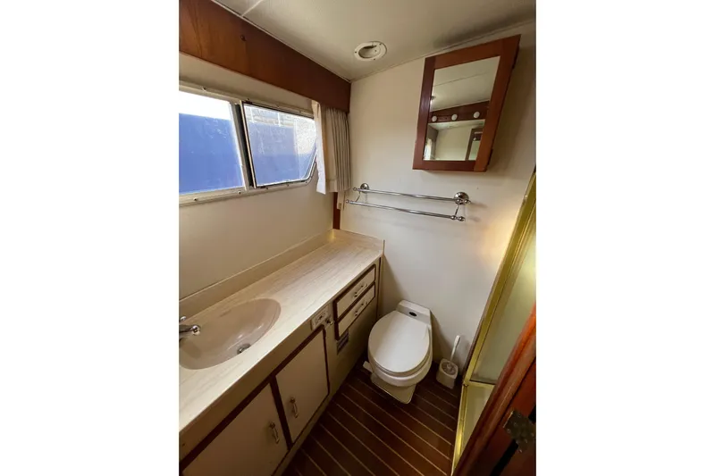 Adios Yacht Photos Pics 1985 Tollycraft 48 Cockpit Motor Yacht bathroom with sink, toilet, and mirror.