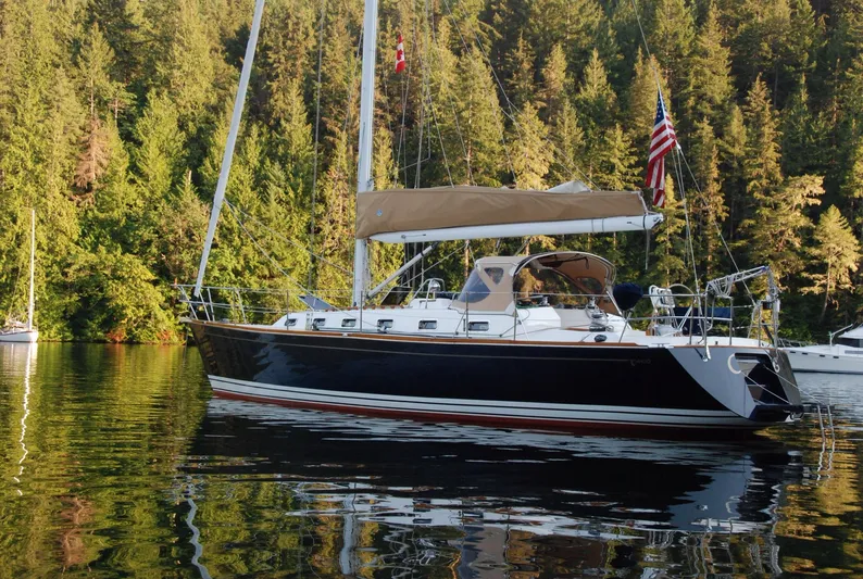 Chance Yacht Photos Pics Sailboat Tartan 4100 (1999) on calm water, surrounded by lush forest.