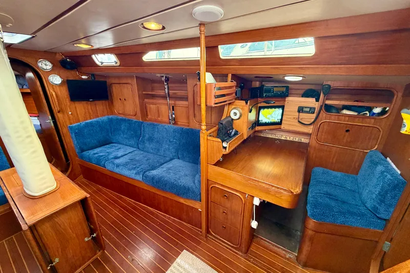 Pacific Pearl Yacht Photos Pics Cozy interior of 1991 Oyster Lightwave 48 yacht with blue seating and navigation equipment.