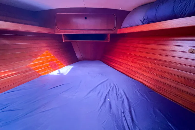 Pacific Pearl Yacht Photos Pics Cozy wooden cabin interior of 1991 Oyster LW48 yacht with blue bedding.