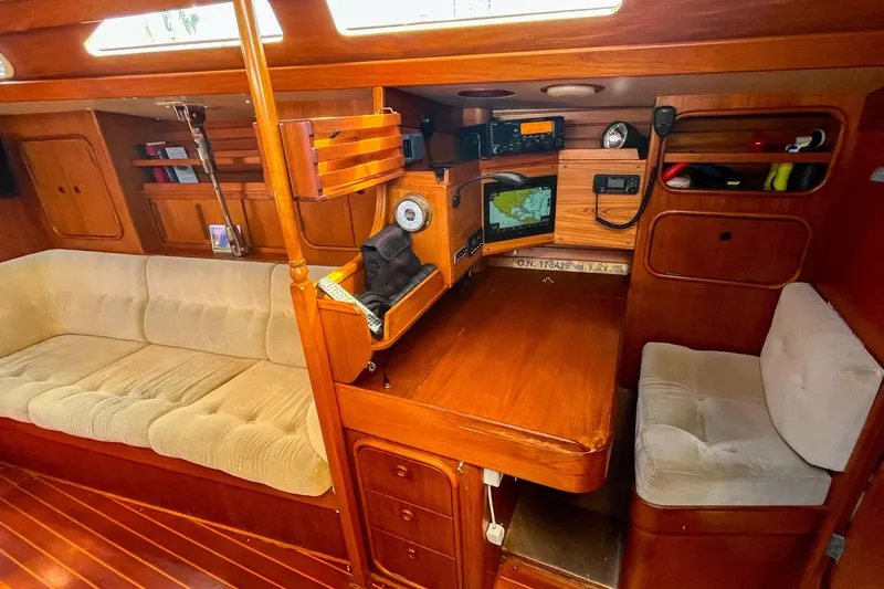 Pacific Pearl Yacht Photos Pics Cozy 1991 Oyster LW48 yacht interior with navigation station and plush seating.