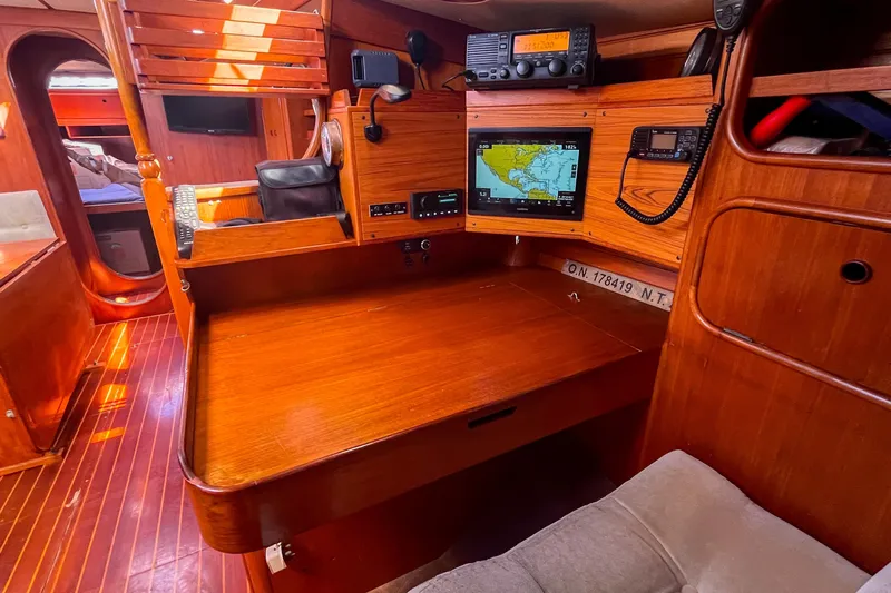 Pacific Pearl Yacht Photos Pics 1991 Oyster LW48 yacht interior with navigation equipment and wooden furnishings.