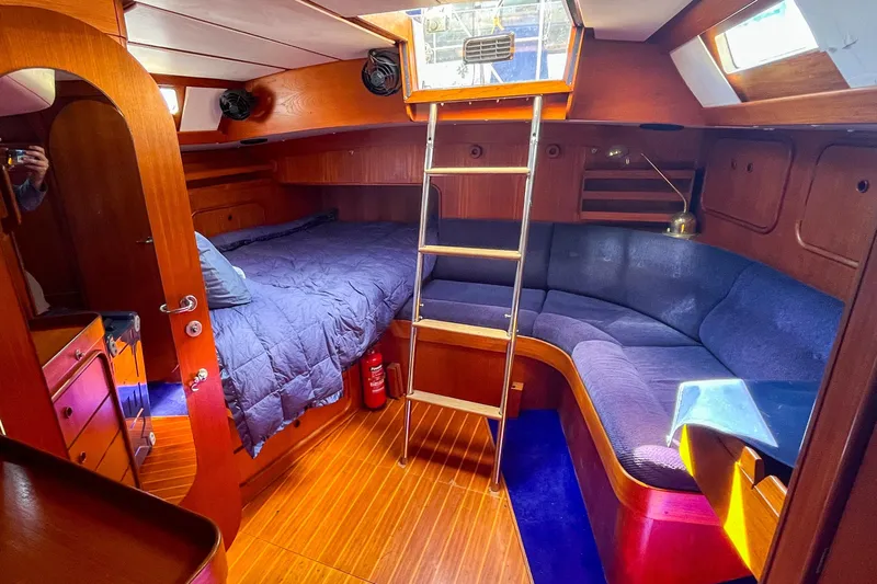 Pacific Pearl Yacht Photos Pics Cozy 1991 Oyster LW48 yacht interior with wooden finish, bed, and seating area.