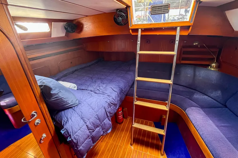 Pacific Pearl Yacht Photos Pics Cozy cabin interior of 1991 Oyster LW48 yacht with wooden finish and blue bedding.