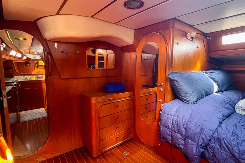 Pacific Pearl Yacht Photos Pics Luxurious 1991 Oyster LW48 yacht interior with wooden cabinetry and cozy bedding.