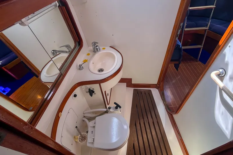 Pacific Pearl Yacht Photos Pics 1991 Oyster LW48 yacht bathroom with sink, toilet, and wooden flooring.
