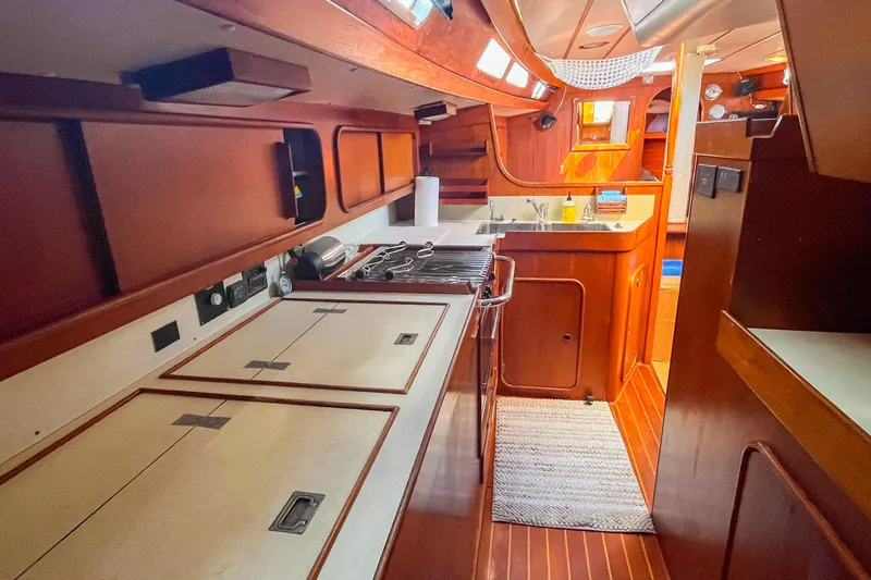 Pacific Pearl Yacht Photos Pics Interior of 1991 Oyster LW48 yacht, featuring a well-equipped kitchen and wooden cabinetry.