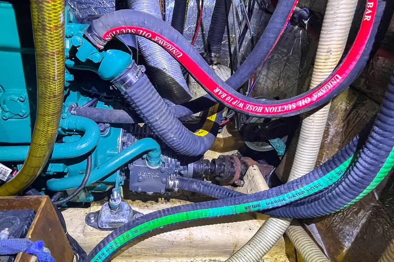 Pacific Pearl Yacht Photos Pics Engine room of 1991 Oyster LW48 yacht with various hoses and mechanical components.