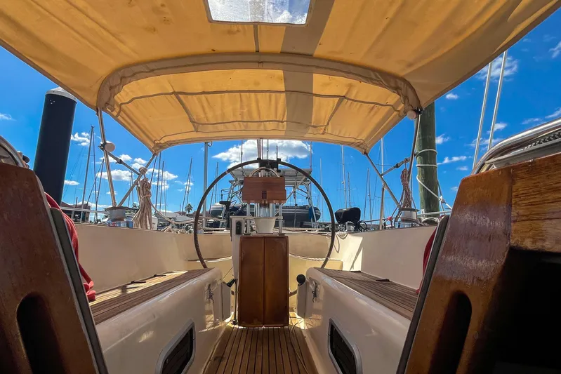 Pacific Pearl Yacht Photos Pics Interior view of 1991 Oyster LW48 sailboat cockpit with wooden accents and canopy.