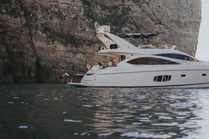  Yacht Photos Pics 2008 Sunseeker Manhattan 70 yacht near rocky cliffs, with people enjoying the water.