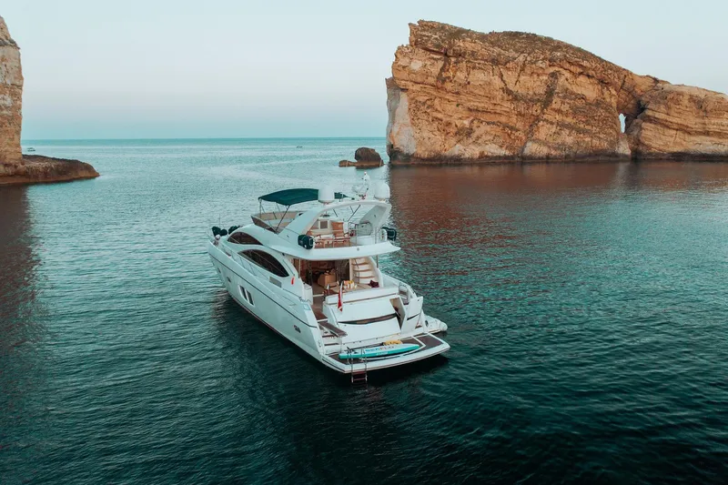  Yacht Photos Pics Luxury Sunseeker Manhattan 70 yacht, 2008 model, anchored near rocky coastal cliffs.