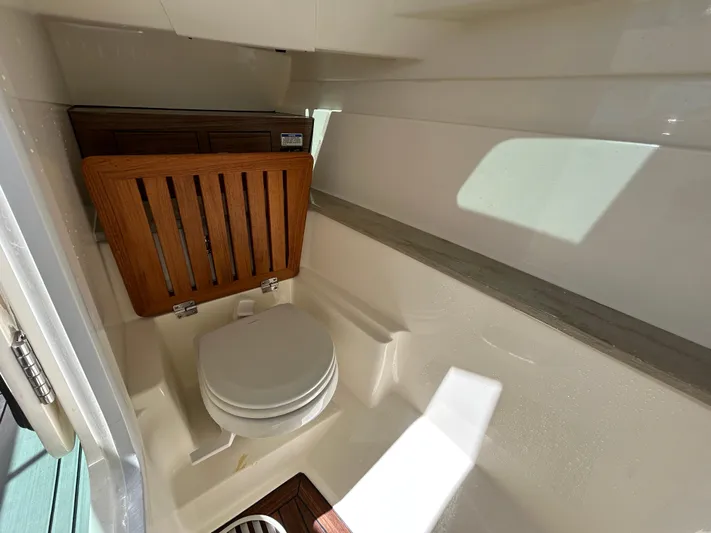  Yacht Photos Pics 2021 Boston Whaler 320 Vantage boat interior with compact marine toilet and wooden accents.