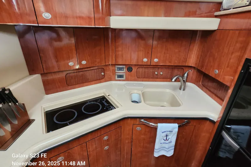 Magnolia Belle Yacht Photos Pics 2004 Sea Ray 390 Motor Yacht kitchen with stove, sink, and wooden cabinetry.