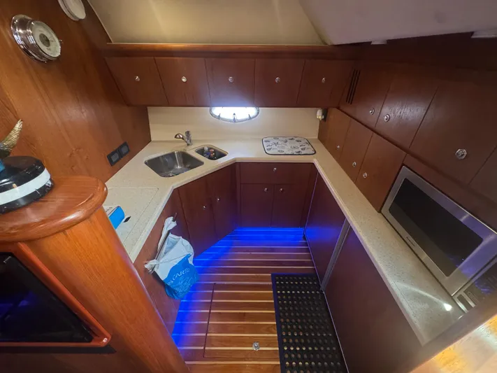  Yacht Photos Pics 2006 Tiara Yachts 4200 Open galley with wood cabinetry, modern appliances, and blue accent lighting.