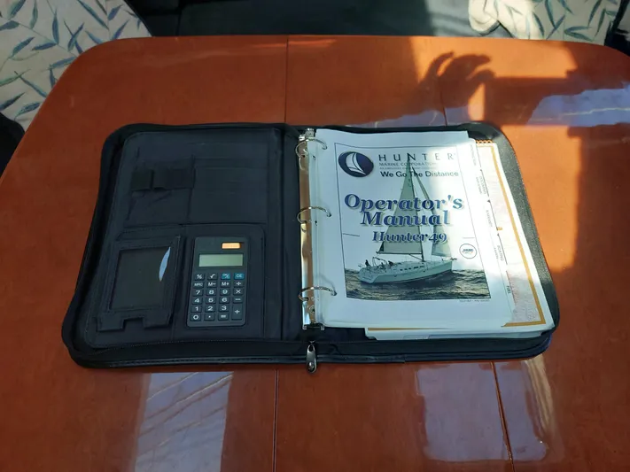 "heron" Yacht Photos Pics Operator's manual for 2009 Hunter 49 yacht on a wooden table with calculator.