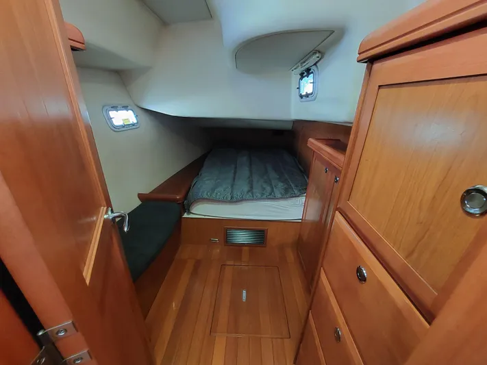 "heron" Yacht Photos Pics Cozy cabin interior of 2009 Hunter 49 sailboat with wooden furnishings and bed.