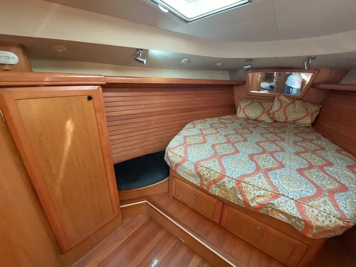 "heron" Yacht Photos Pics Cozy cabin interior of 2009 Hunter 49 sailboat with wood paneling and patterned bedding.