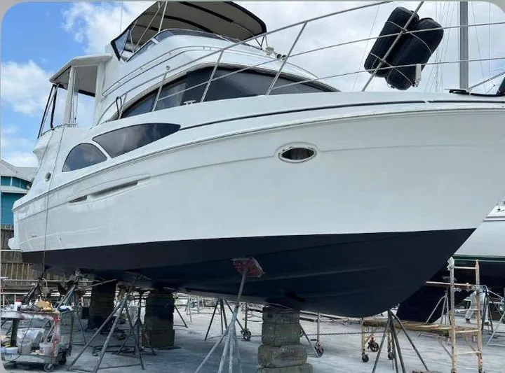 Miracles Yacht Photos Pics 2006 Carver 41 Cockpit Motor Yacht on dry dock, white hull, blue bottom, clear sky.