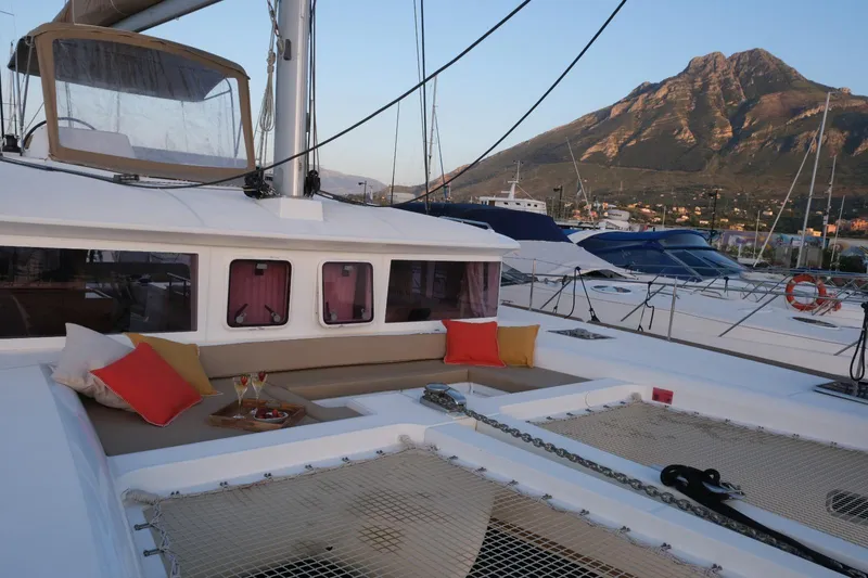 Pasha Yacht Photos Pics Lagoon 450F catamaran with mountain backdrop, featuring cozy seating and colorful cushions.