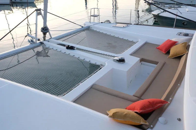 Pasha Yacht Photos Pics Lagoon 450F 2012 catamaran deck with seating, colorful cushions, and netting at sunset.