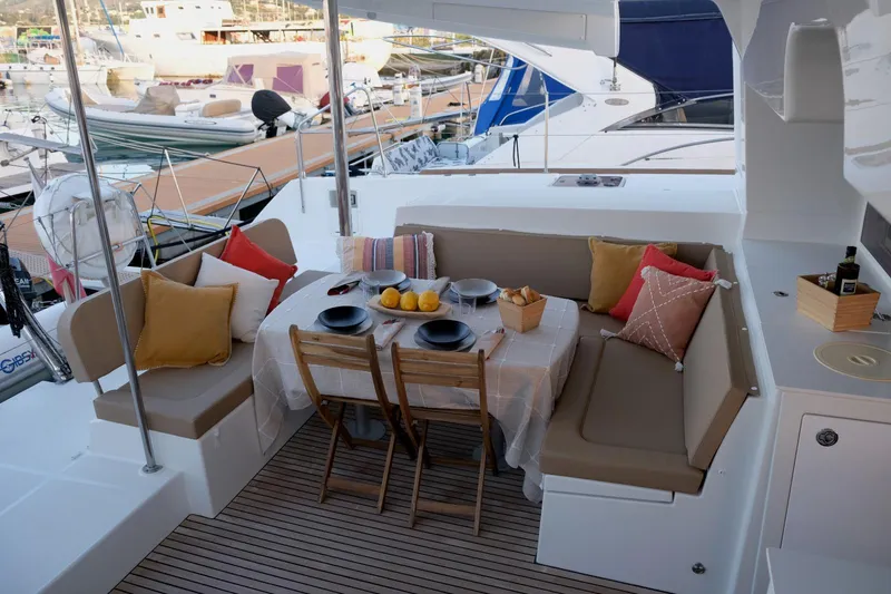 Pasha Yacht Photos Pics Outdoor dining area on 2012 Lagoon 450F yacht with table, chairs, and colorful cushions.