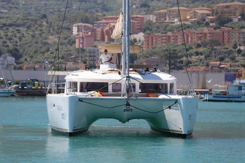 Pasha Yacht Photos Pics 2012 Lagoon 450F catamaran sailing in a scenic harbor with hillside buildings.
