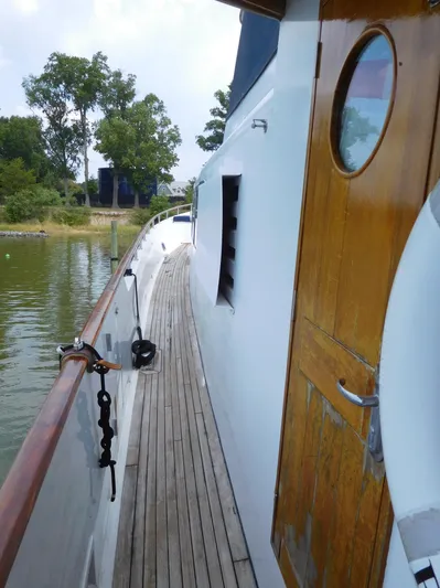  Yacht Photos Pics 1983 Cheoy Lee 90 cockpit motor yacht, wooden deck and cabin door, docked by lush greenery.