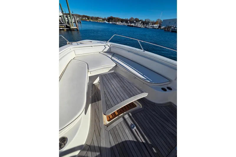  Yacht Photos Pics 2013 Boston Whaler 320 Outrage boat interior with seating and table, docked by the water.