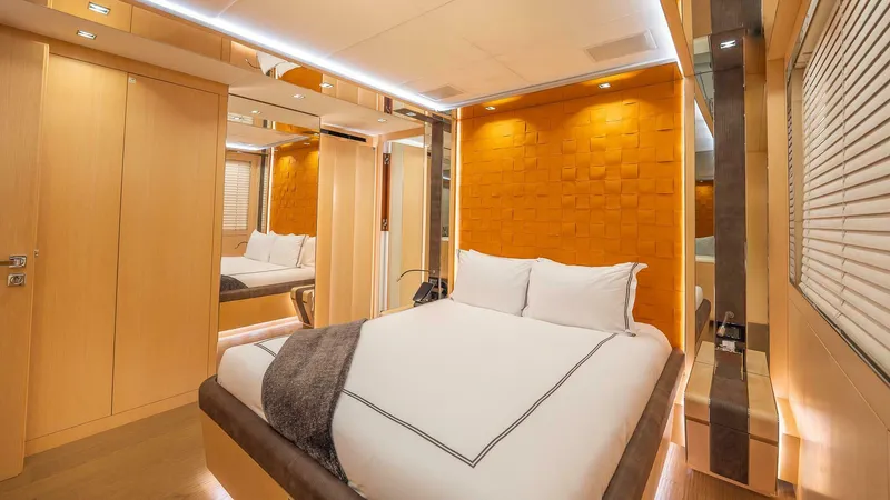 Neverland Yacht Photos Pics Luxurious bedroom interior on 2016 Mangusta Oceano 42 yacht, featuring modern design and warm lighting.