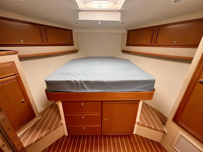 Pacific Adventures Yacht Photos Pics 2008 Cabo 52 Express cabin with bed, wooden cabinets, and storage drawers.