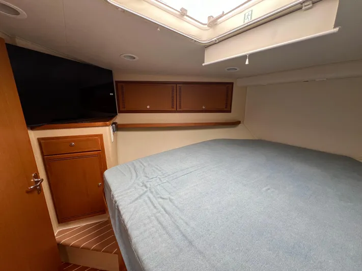 Pacific Adventures Yacht Photos Pics 2008 Cabo 52 Express cabin interior with bed, TV, and wooden cabinetry.