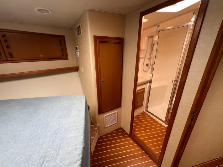 Pacific Adventures Yacht Photos Pics 2008 Cabo 52 Express cabin interior with bed and bathroom, featuring wood accents.