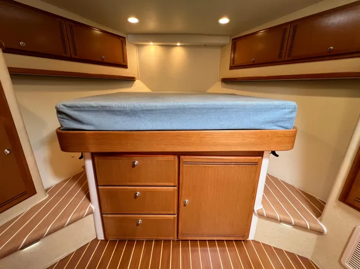 Pacific Adventures Yacht Photos Pics 2008 Cabo 52 Express cabin interior with bed, wooden cabinets, and striped flooring.