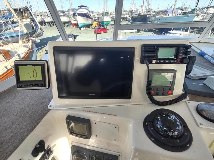 Journey Yacht Photos Pics Control panel of a 2002 Endeavour Trawlercat 36 with navigation instruments and marina view.