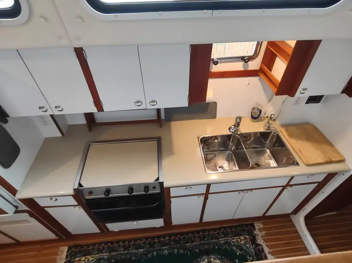 Journey Yacht Photos Pics Kitchen area of 2002 Endeavour Trawlercat 36 with stove, sink, and wooden cabinetry.