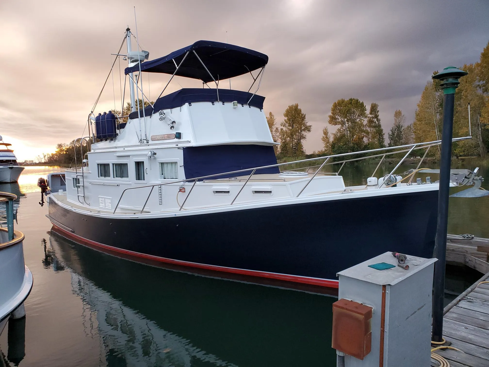 1970 Custom Tri-Cabin boat docked at sunset, featuring a sleek navy and white design.