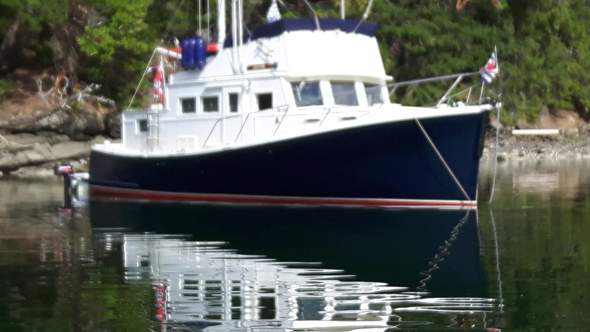 1970 Custom Tri-Cabin boat on calm water, surrounded by lush greenery.