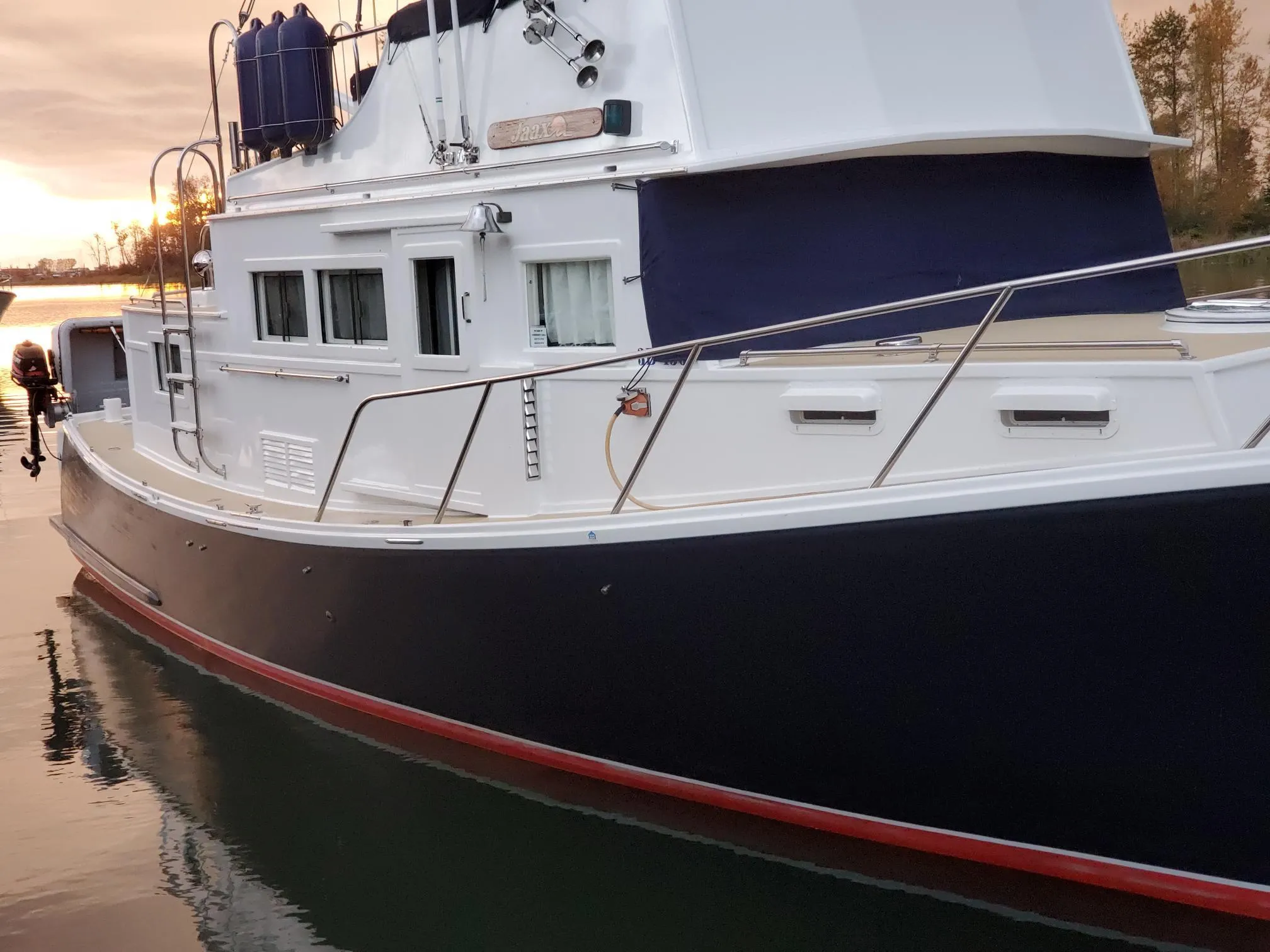 1970 Custom Tri-Cabin boat on calm water at sunset.