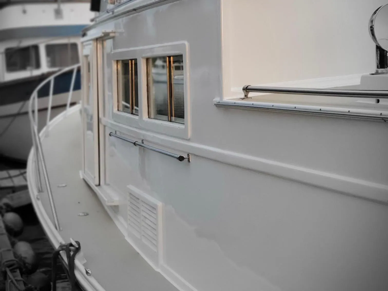 1970 Custom Tri-Cabin boat with sleek white exterior and multiple windows, docked at marina.