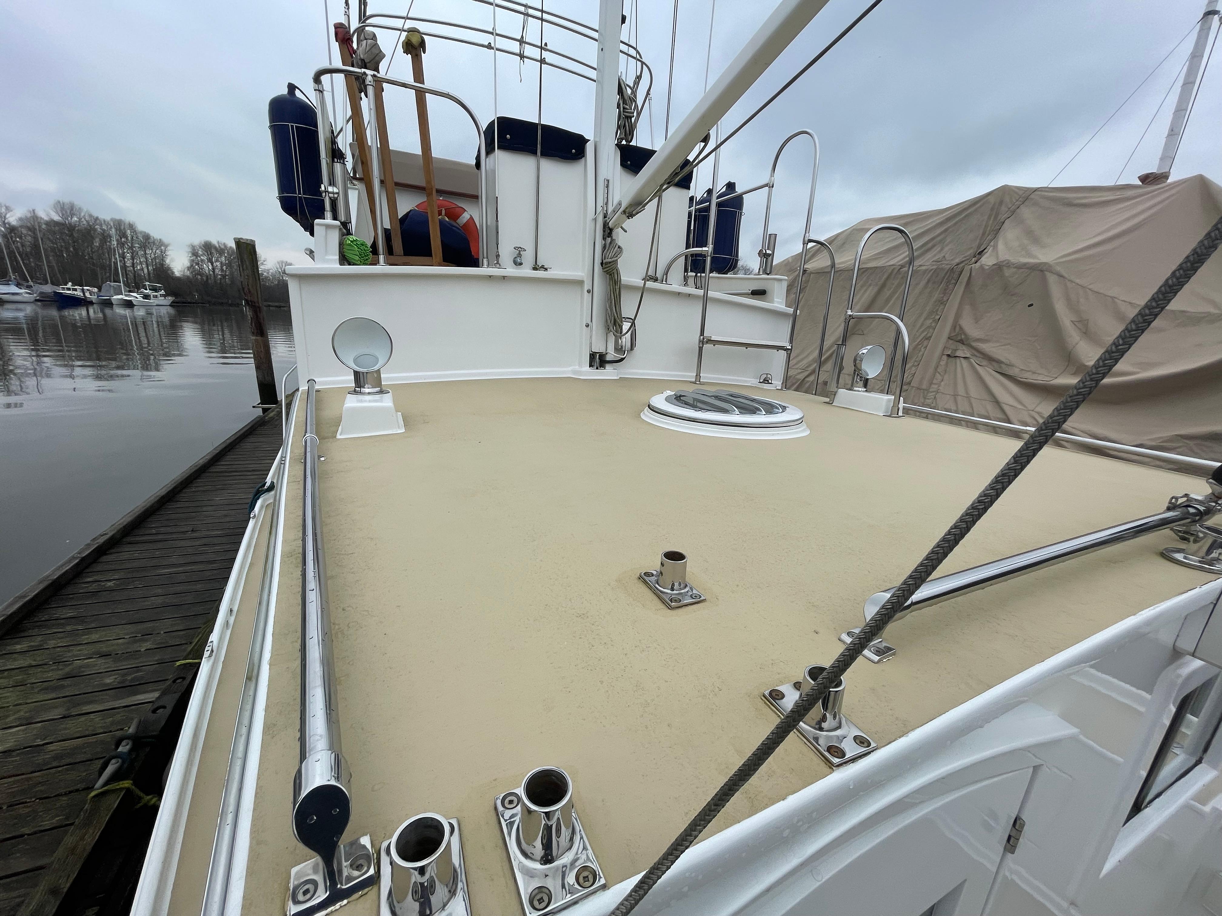 1970 Custom Tri-Cabin boat deck with railing, docked at marina under cloudy sky.