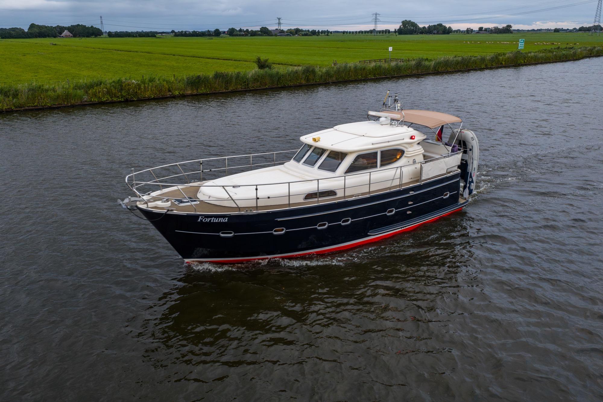 Elling E3 Ultimate 2001 yacht cruising on a serene river with lush green banks.