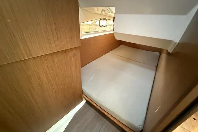  Yacht Photos Pics 2020 Jeanneau NC 1095 Fly cabin interior with bed and wooden paneling.