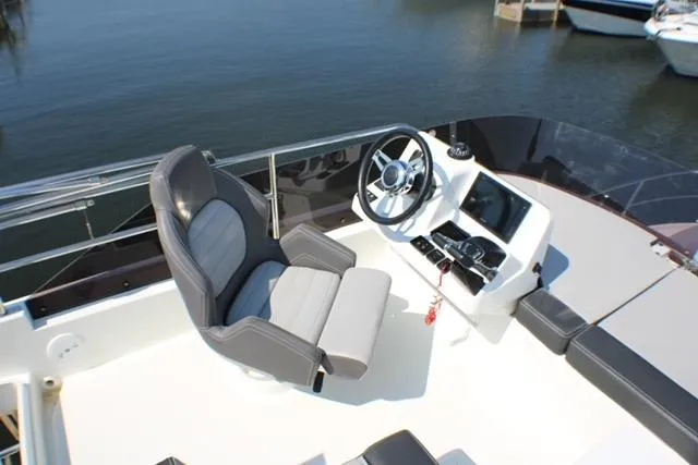  Yacht Photos Pics Flybridge helm of 2020 Jeanneau NC 1095 Fly with steering wheel and captain's chair.