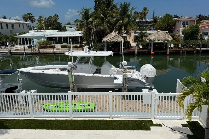  Yacht Photos Pics 2023 Jupiter 32 boat docked by waterfront homes with palm trees and clear skies.